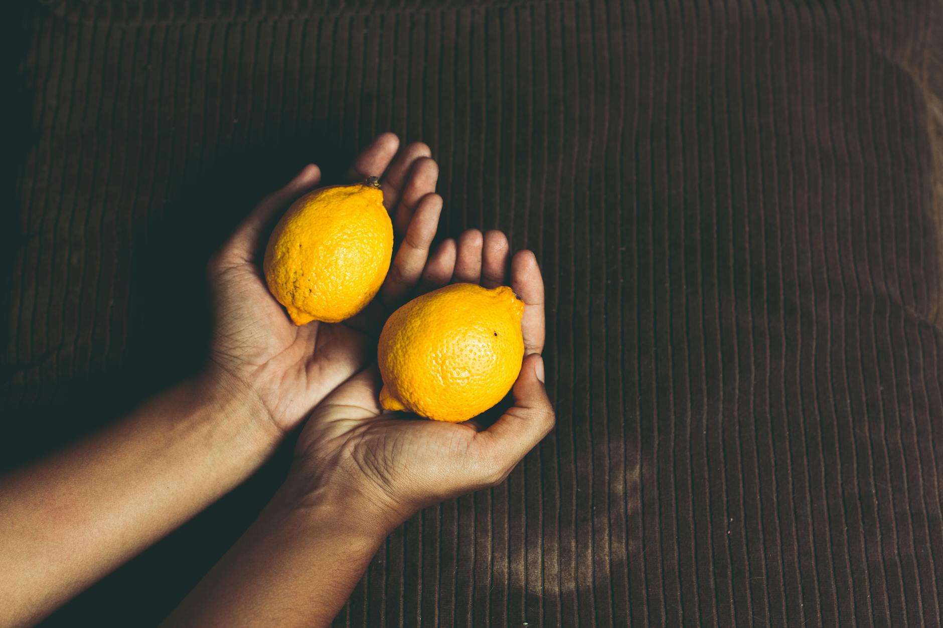Two fresh lemons held in cupped hands symbolizing renewal and freshness