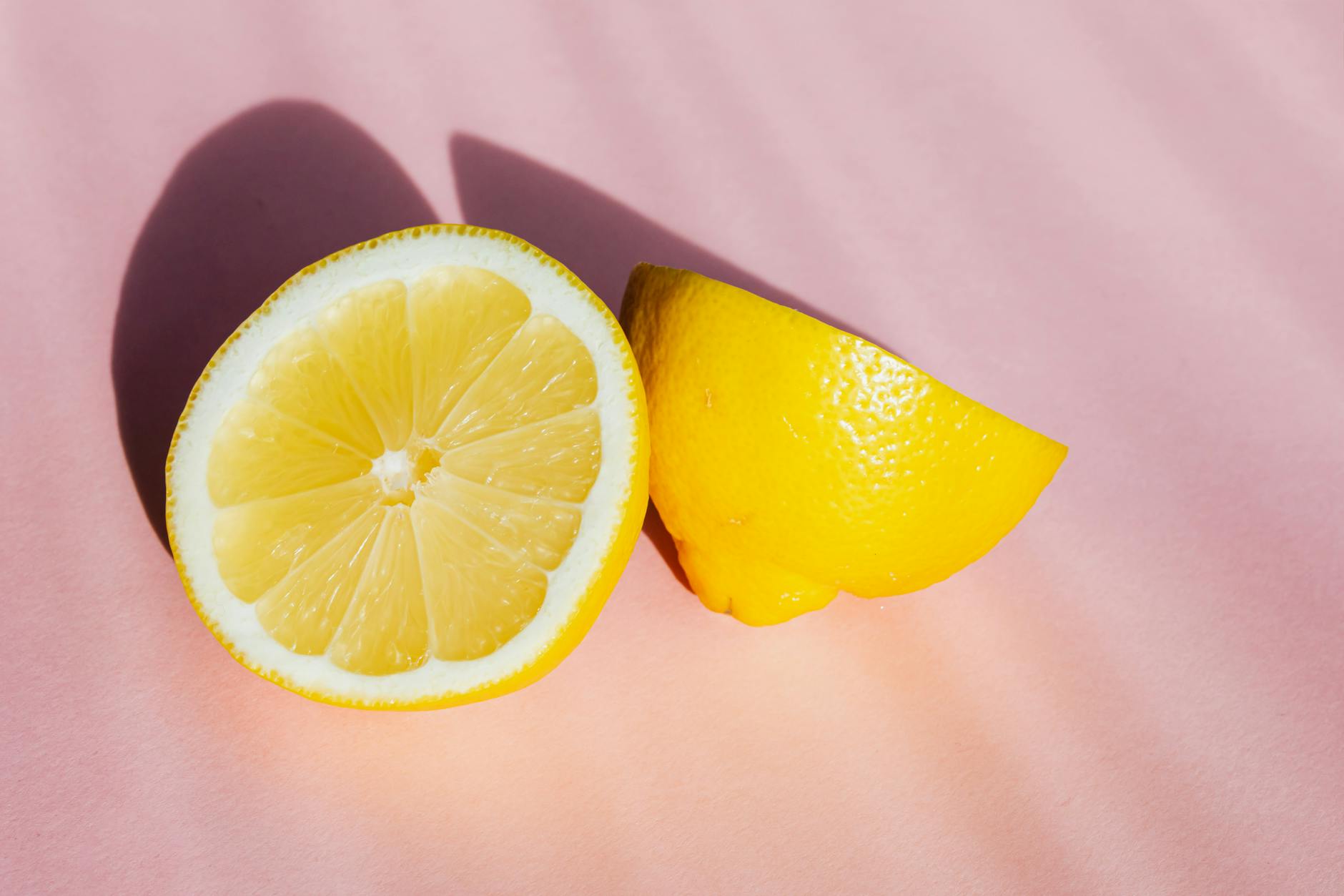 Fresh lemons halved on a pink background in sunlight, representing fresh approaches to partnered pleasure