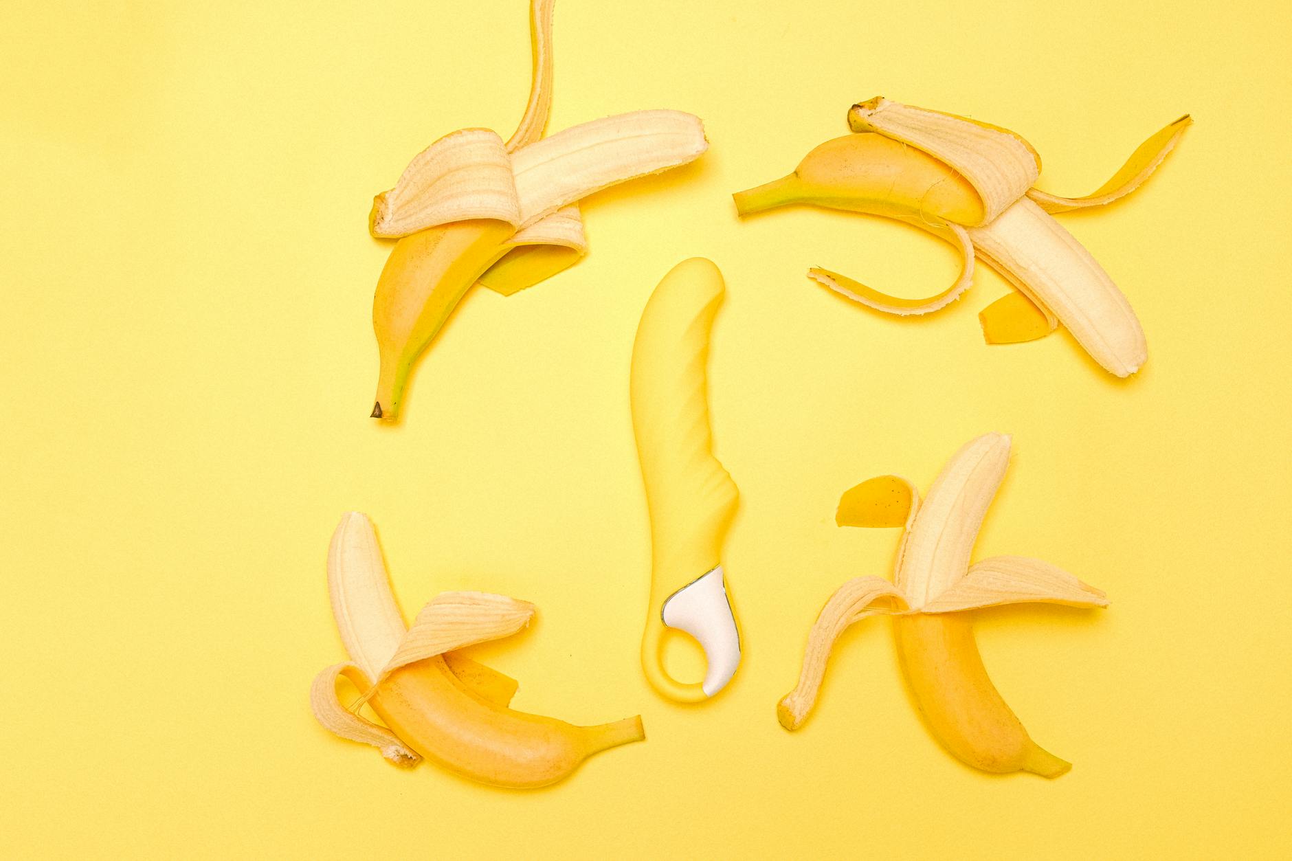 Yellow lemon vibrator on a bright yellow background surrounded by fresh lemons