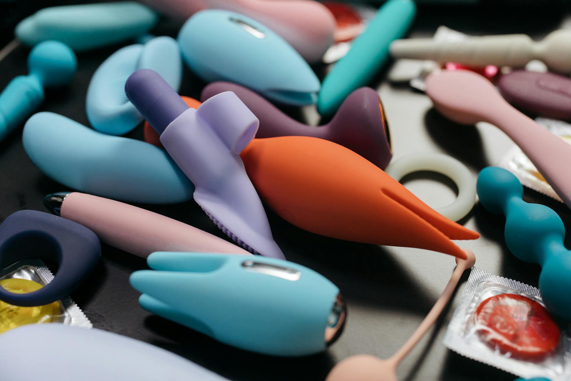 A hand holding an orange vibrator against a minimalistic purple backdrop, showcasing modern sensuality.