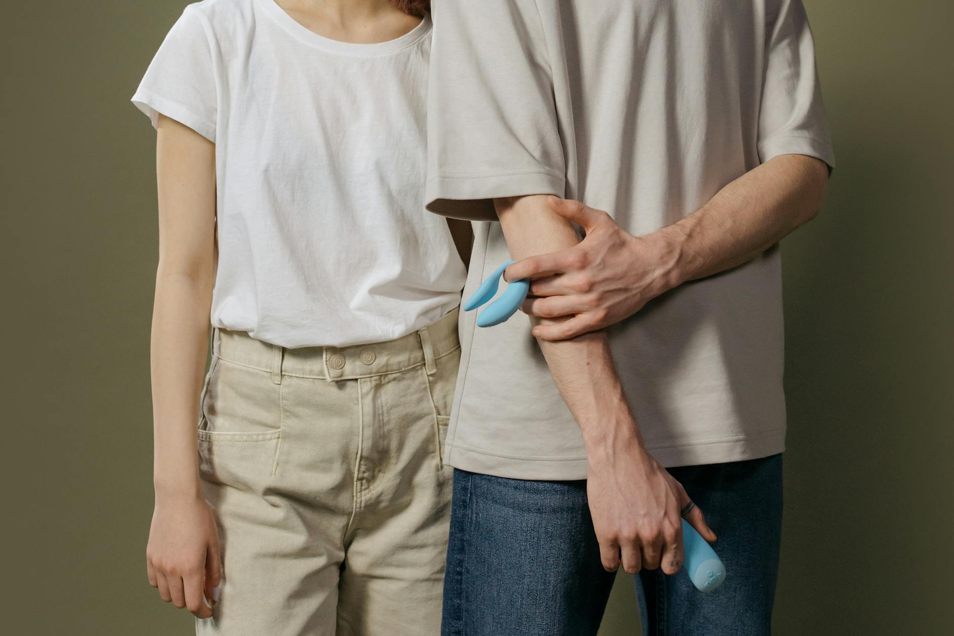 A young couple holding a blue suction vibrator together, exploring modern intimacy tools.