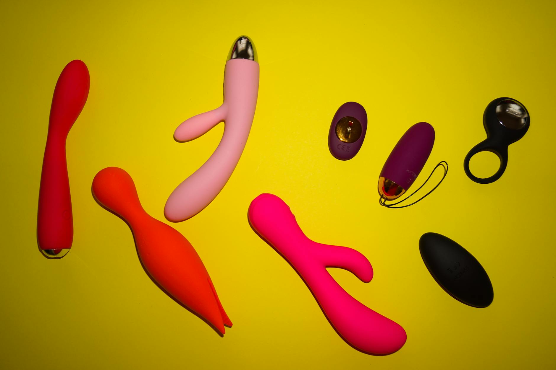Woman thoughtfully holding blue and pink silicone vibrators, exploring pleasure after recovery